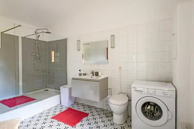 a bathroom with a shower toilet and a washing machine at Mas de l'Aube in Mouriès