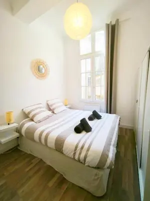 a white bedroom with a large bed with pillows at T2 lumineux plein centre à 5 min du Cours Mirabeau confort, wifi, cuisine équipée in Aix-en-Provence