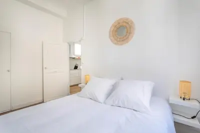 a white bedroom with a white bed and a mirror at T2 lumineux plein centre à 5 min du Cours Mirabeau confort, wifi, cuisine équipée in Aix-en-Provence