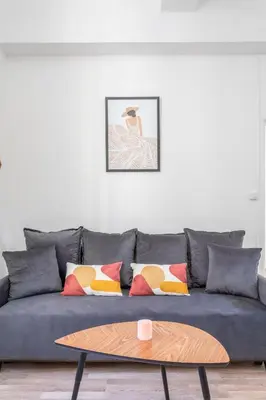 a living room with a blue couch with pillows and a table at T2 lumineux plein centre à 5 min du Cours Mirabeau confort, wifi, cuisine équipée in Aix-en-Provence