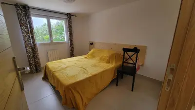 a bedroom with a bed and a chair and a window at Le PEROTIN in Villes-sur-Auzon