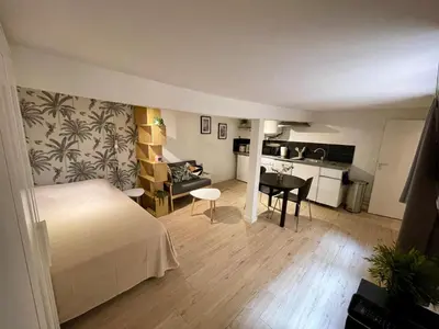 a bedroom with a bed and a table and a kitchen at Studio Tout confort Centre historique rue calme Climatisation in Aix-en-Provence