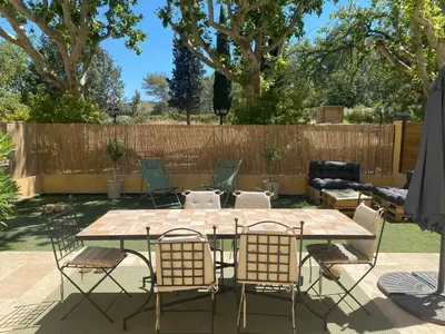 a table and chairs in a backyard with a fence at Appartement de standing dans une bastide Aixoise in Aix-en-Provence