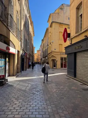 a woman walking down a street in a city at Le Loft de Roxane Centre historique Aix en Provence in Aix-en-Provence