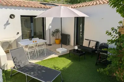 a patio with a table and an umbrella and chairs at Maison moderne jardin piscine et parking prives, près d'Aix Centre in Venelles