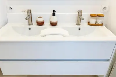 a white bathroom sink with two faucets at Maison moderne jardin piscine et parking prives, près d'Aix Centre in Venelles