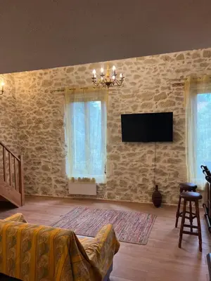 a living room with a tv on a stone wall at Chez Dragos centre ville Lauris in Lauris