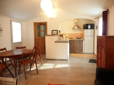 a kitchen and dining room with a table and a refrigerator at Aix en Provence charmante villa piscine cadre verdoyant 6 personnes in Aix-en-Provence