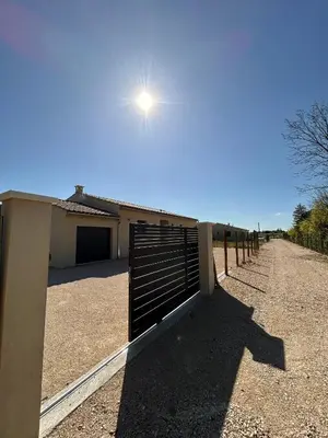 a fence in front of a building with the sun overhead at Villa en Provence avec piscine in Mollégès