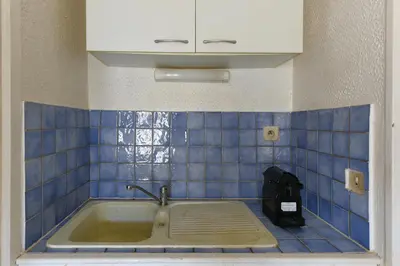 a bath tub in a blue tiled bathroom with a sink at Studio Lavande in La Fare-les-Oliviers