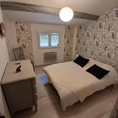 a bedroom with a white bed and a table at Maison au coeur du Lubéron in Maubec