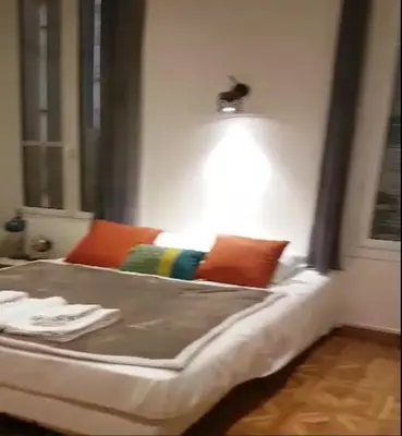 a bed with pillows and a light on the wall at Hôtel des ARTS Aix in Aix-en-Provence