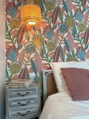 a bedroom with a floral wallpaper and a bed and a dresser at Calussine maison provençale in Pernes-les-Fontaines