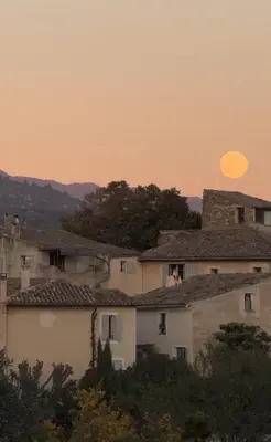 a sun setting in the sky over a group of houses at La Bergerie de Chateau Fontvert in Lourmarin