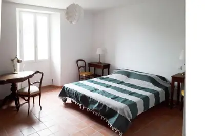 a bedroom with a bed and a table and a window at La Maison Cassée in Malemort-du-Comtat