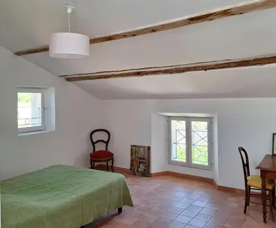 a bedroom with a green bed and a table and chairs at La Maison Cassée in Malemort-du-Comtat