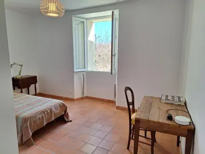 a room with a bed and a table and a window at La Maison Cassée in Malemort-du-Comtat