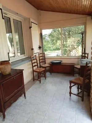 a living room with chairs and a table and windows at La garenne basse chez Sylvie in Saint-Didier