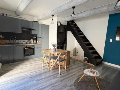 a kitchen with a wooden table and a staircase at Le Nid Provençal in Lambesc
