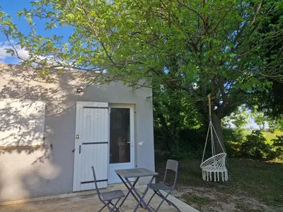 a patio with a table and chairs under a tree at le mazet de LOÏS in Carpentras