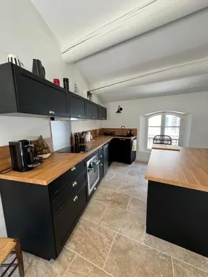 a large kitchen with black cabinets and wooden counter tops at La bohème in Lourmarin