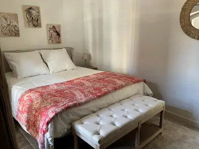 a bed with a red and white blanket and a bench at La bohème in Lourmarin
