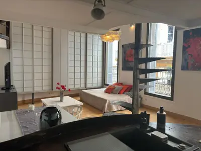 a living room with a bed and a spiral staircase at Le Loft du Matheron in Aix-en-Provence