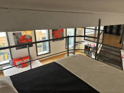 a loft bed in a room with a large window at Le Loft du Matheron in Aix-en-Provence