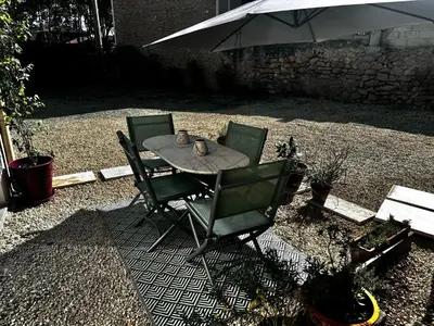 a table with two chairs and an umbrella at Charmant T2 atypique proche du centre-ville in Miramas