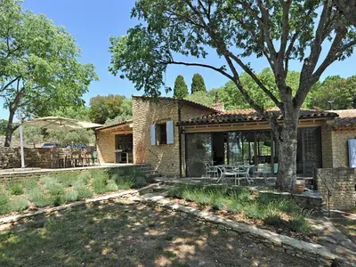 a brick house with a patio and a tree at Le Chant des Bories in Gordes