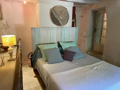 a bedroom with a bed with blue pillows and a mirror at Charmante Maison au cœur du village in Rustrel
