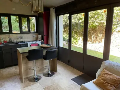 a kitchen with a table and two bar stools at Charmante Maison au cœur du village in Rustrel