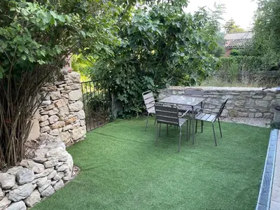 a table and chairs in a garden with grass at Charmante Maison au cœur du village in Rustrel