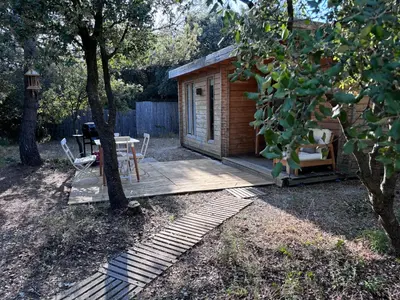 a wooden cabin with a table and chairs on a deck at Éco Lodge - Nature et Spa in Aurons