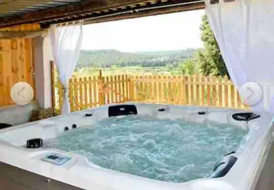 a hot tub in a backyard with a window at Éco Lodge - Nature et Spa in Aurons