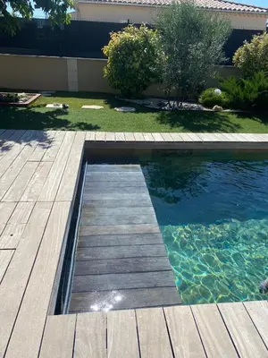 a swimming pool with a wooden deck and water at La bastide de marie in Robion en Luberon