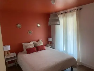 a bedroom with a white bed with red pillows at Maison avec piscine et jacuzzi proche de la rivière idéale pour un séjour détente in Le Thor