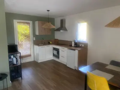 a kitchen with white cabinets and a wooden floor at Maison avec piscine et jacuzzi proche de la rivière idéale pour un séjour détente in Le Thor