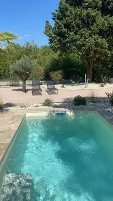 a large pool of blue water in a yard at Maison avec piscine et jacuzzi proche de la rivière idéale pour un séjour détente in Le Thor
