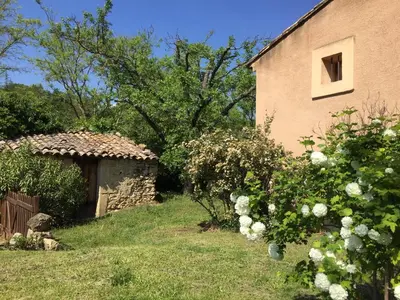 a house with a building and a yard with flowers at La maison Danna in Lauris