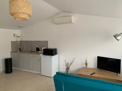 a room with a kitchen with a counter and a table at Studio le soleil couchant in Saint-Saturnin-lès-Avignon