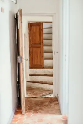 an empty hallway with a wooden door and stairs at Le Bas Château Provence Luberon in Saint-Michel-lʼObservatoire