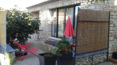 a patio with a red umbrella and some plants at La cigale bleue in Gordes