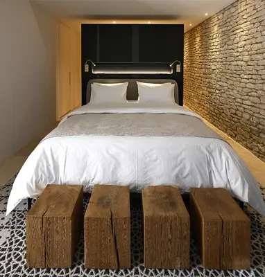 a bedroom with a bed with two wooden stools next to it at La Suite Gordes in Gordes
