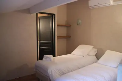 two beds in a room with white sheets at Le Gîte du Hameau Fleur de Pierres in Gordes