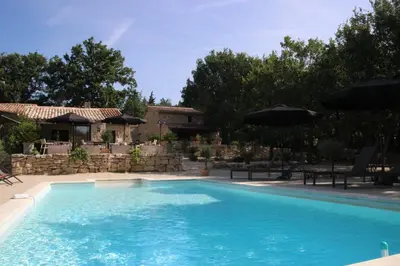 a swimming pool in front of a house at Le Gîte du Hameau Fleur de Pierres in Gordes