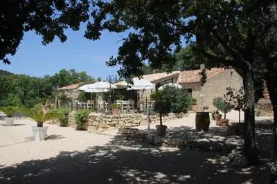 a building with a tree and a building with a patio at Le Gîte du Hameau Fleur de Pierres in Gordes