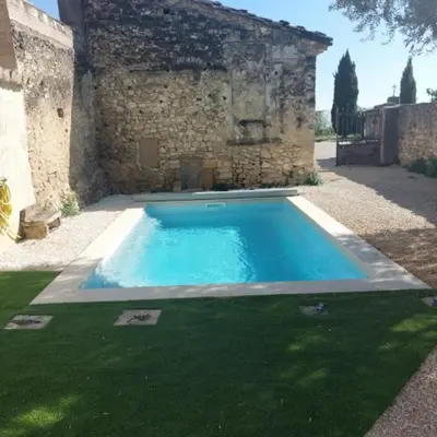 a swimming pool in front of a stone building at La maison d'Antoine à Robion in Robion en Luberon