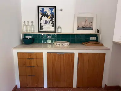 a kitchen counter with wooden cabinets and green tiles at Les Noyers in Montjustin