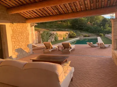 a patio with a couch and a table and a pool at Les Noyers in Montjustin